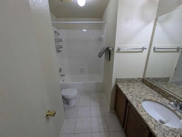 a bathroom with a granite countertop sink a toilet and shower