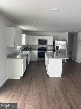 a living room with stainless steel appliances a kitchen island hardwood floor sink and stove