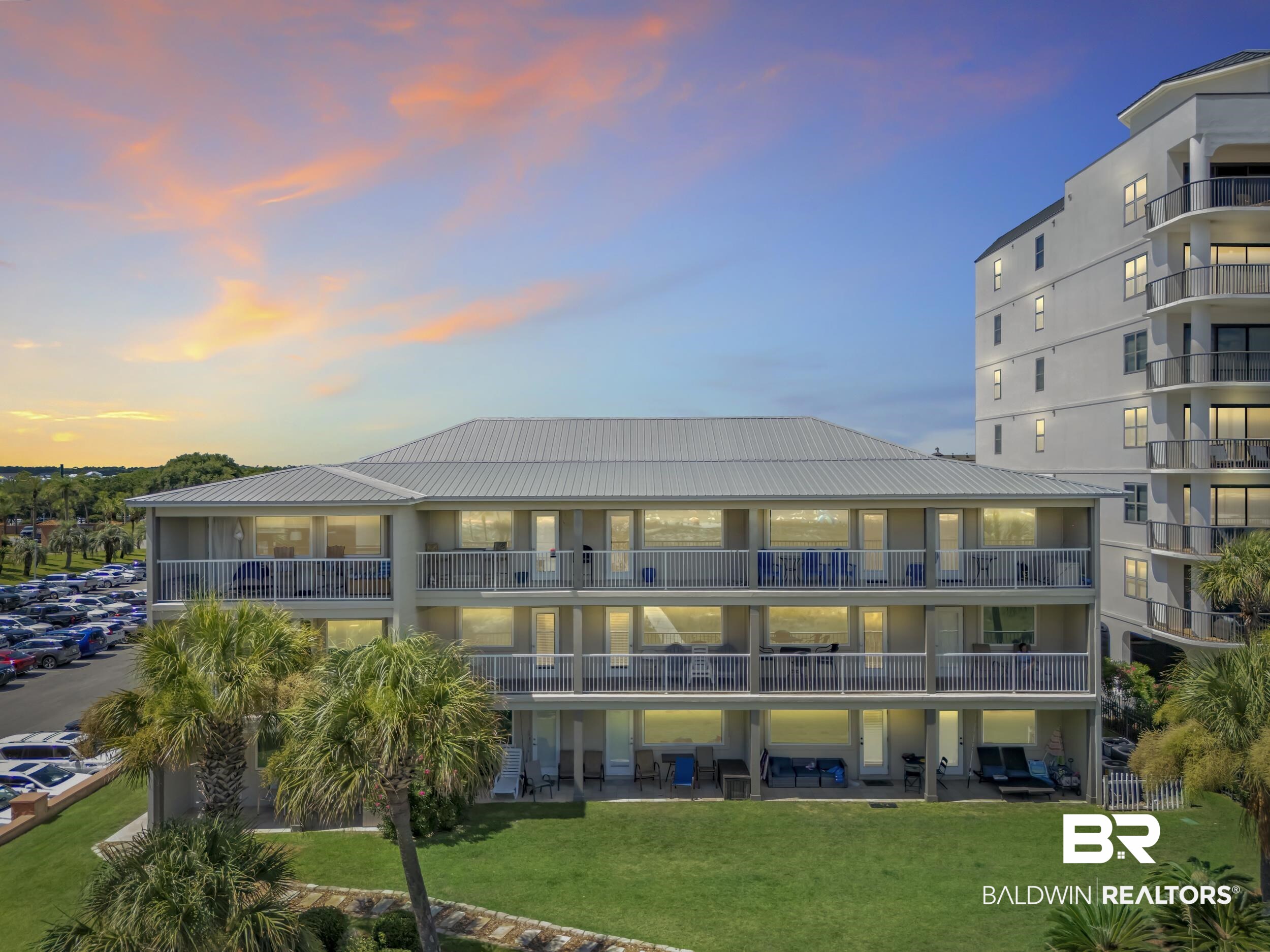 27222 Gulf Road, Unit 33 Orange Beach, AL 36561 - Photo 1 of 29 Multi-story condominium building featuring private balconies, a metal roof, and a manicured lawn