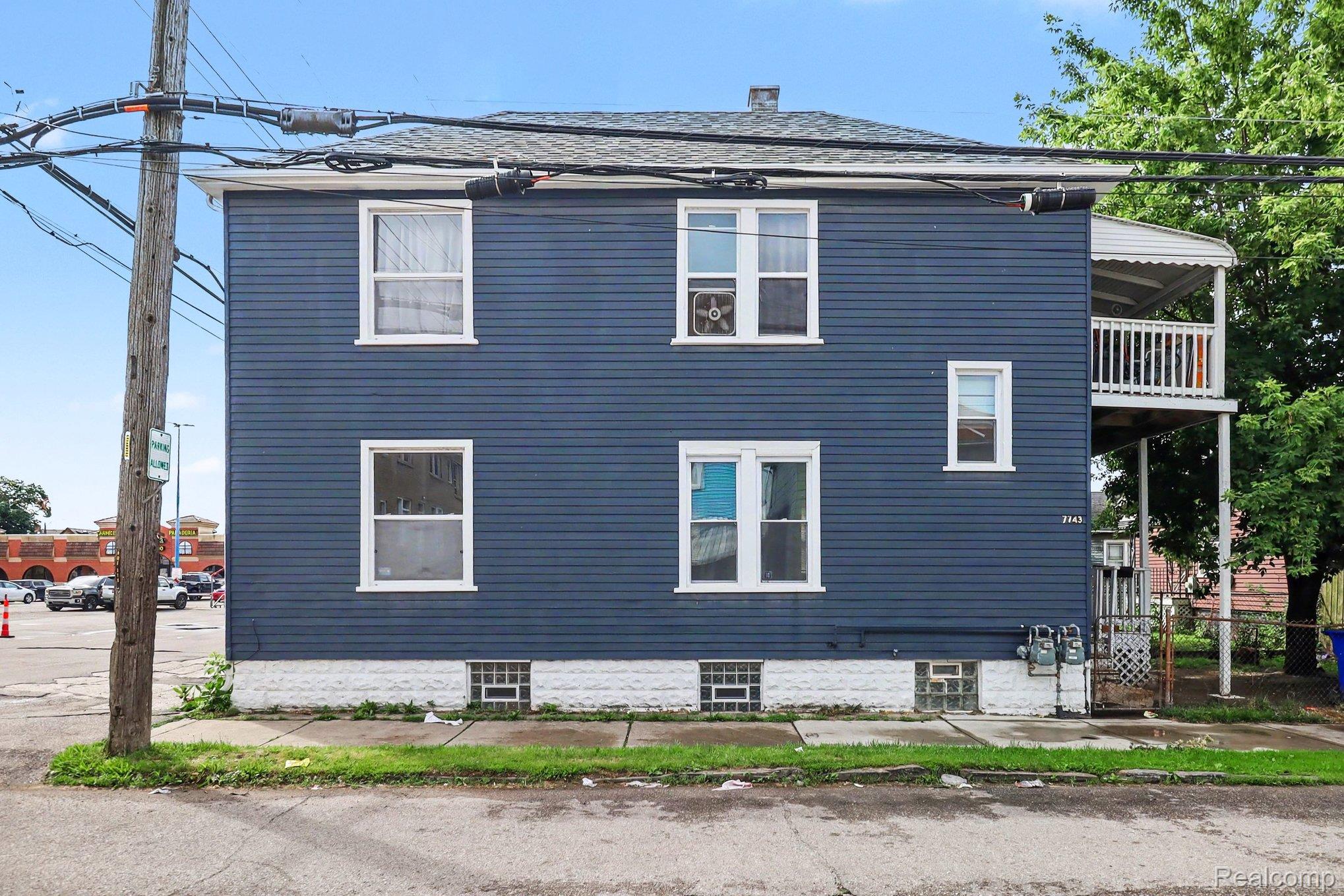 7743 Pitt Street Detroit, MI 48209 - Photo 4 of 15 Two-story property featuring horizontal siding, white trim windows, and a basement with glass block windows