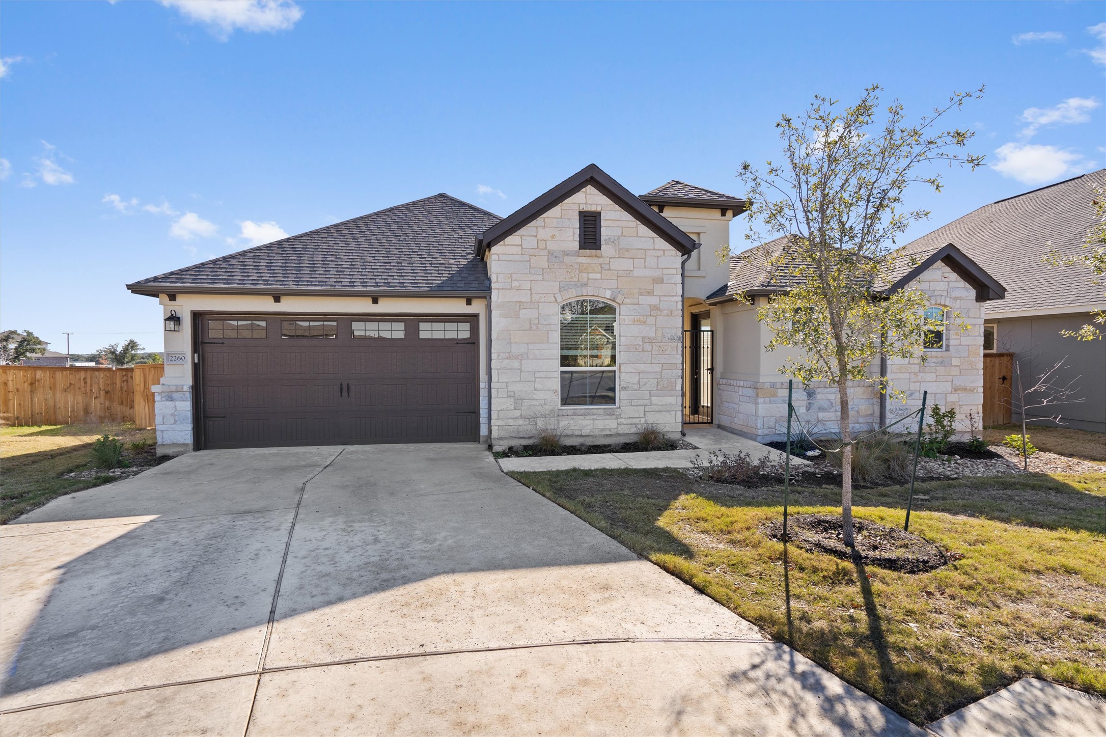 French provincial home with stone siding, driveway, a shingled roof, and a garage