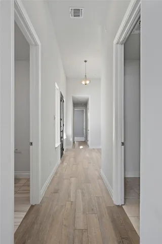 a view of a hallway with wooden floor and a bathroom
