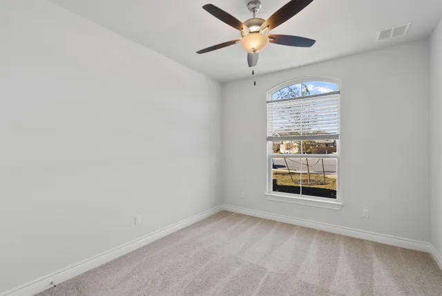 an empty room with windows and fan