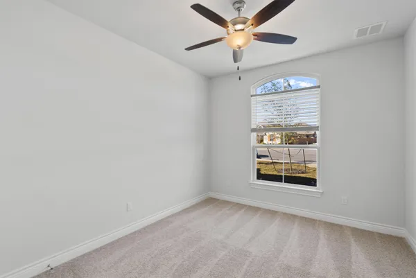 an empty room with windows and fan