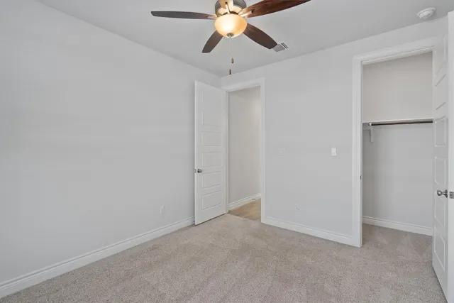 a view of an empty room and chandelier fan