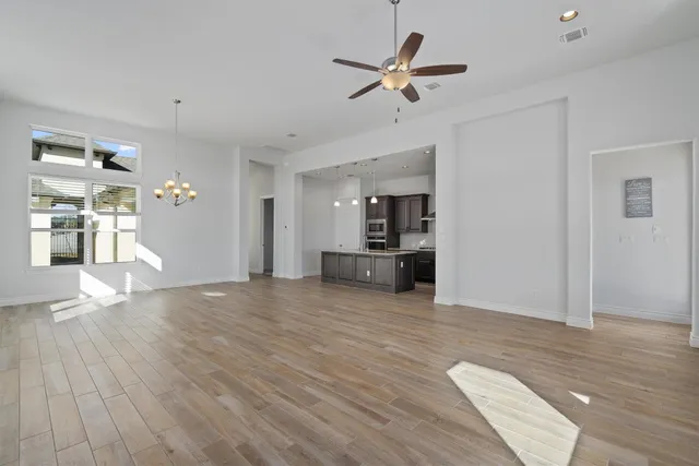 a view of empty room with wooden floor and ceiling fan