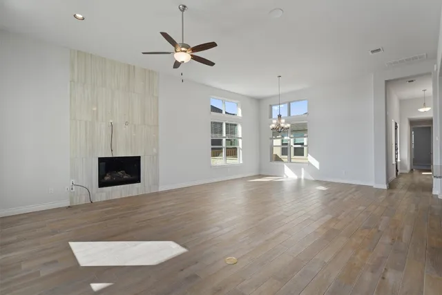 a view of a livingroom with a fireplace a ceiling fan and wooden floor