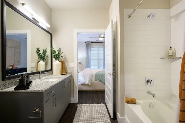 a en suite bathroom with a granite countertop tub sink and mirror