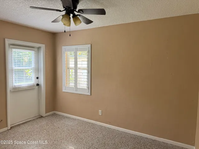 an empty room with windows and fan