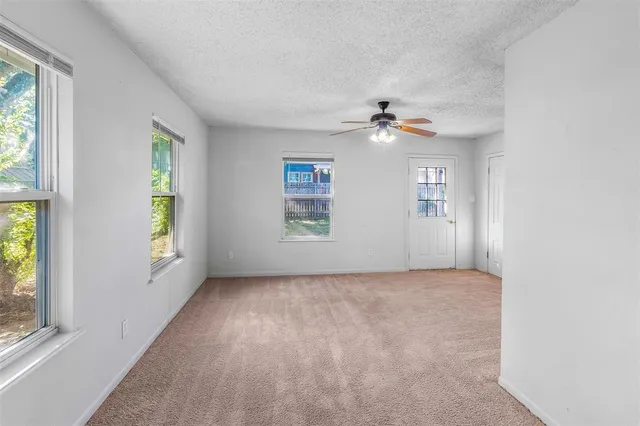 an empty room with windows and fan