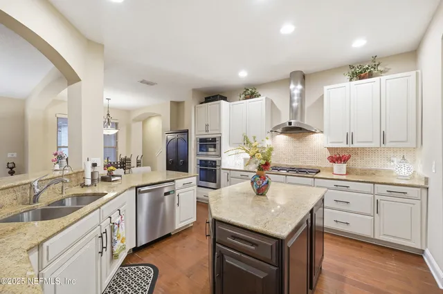 a kitchen with a sink stove cabinets and wooden floor