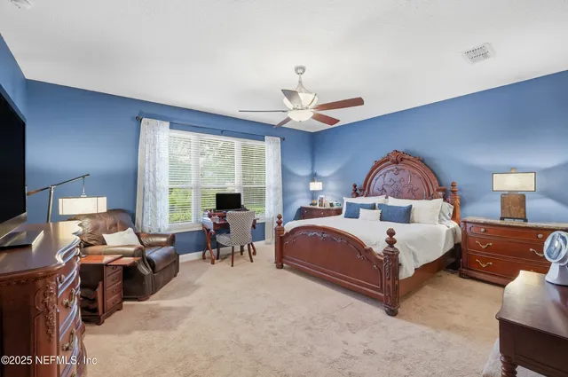 a spacious bedroom with a bed a chandelier and a dresser