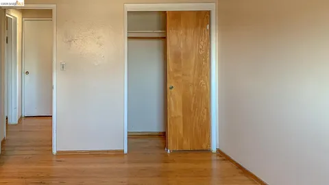 a view of empty room with wooden floor and electronic appliances