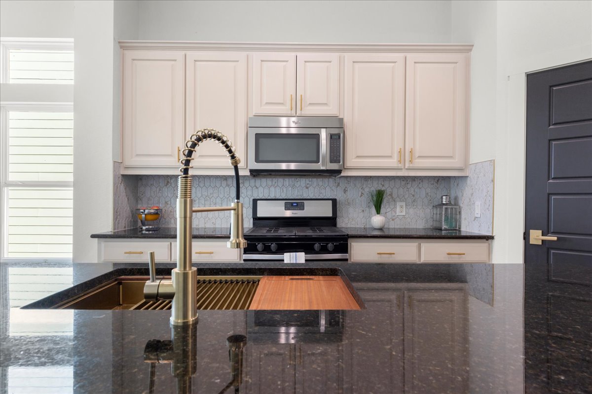 2408 Vintage Stave Road, Unit 101 Austin, TX 78748 - Photo 5 of 32 Kitchen with dark stone counters, tasteful backsplash, and appliances with stainless steel finishes