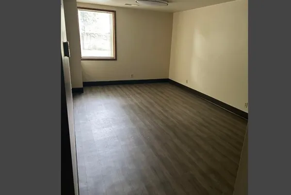 an empty room with wooden floor and windows