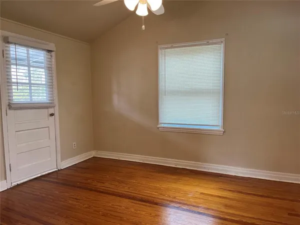 a view of empty room with wooden floor and fan