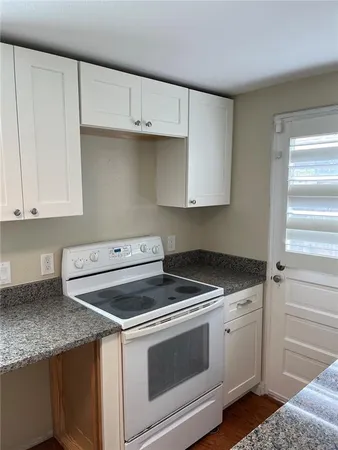a kitchen with granite countertop white cabinets and white appliances