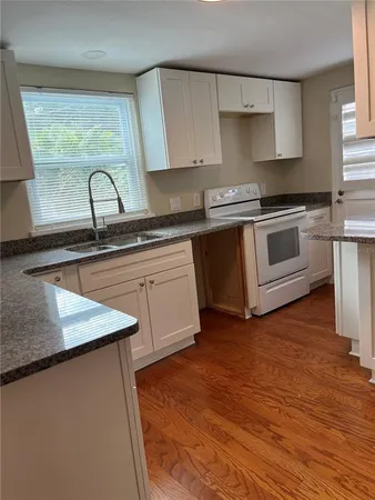 a kitchen with granite countertop white cabinets and white appliances