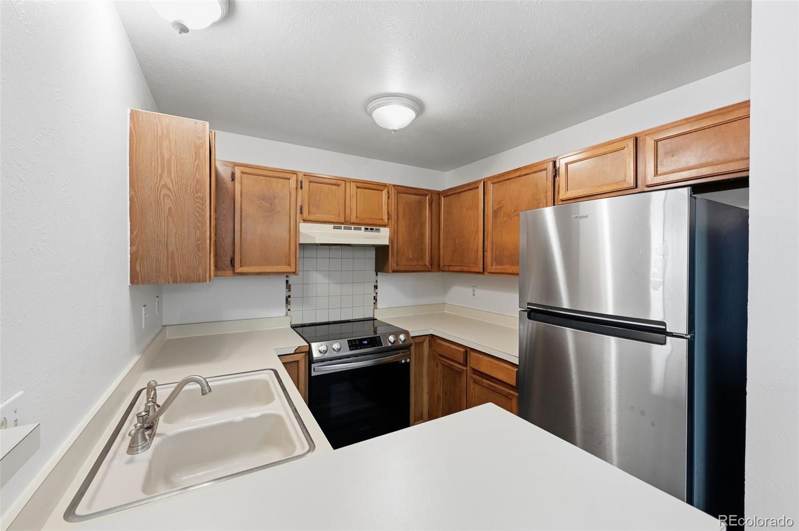 7883 Allison Way, Unit 302 Arvada, CO 80005 - Photo 16 of 29 a kitchen with a refrigerator a stove top oven and cabinets