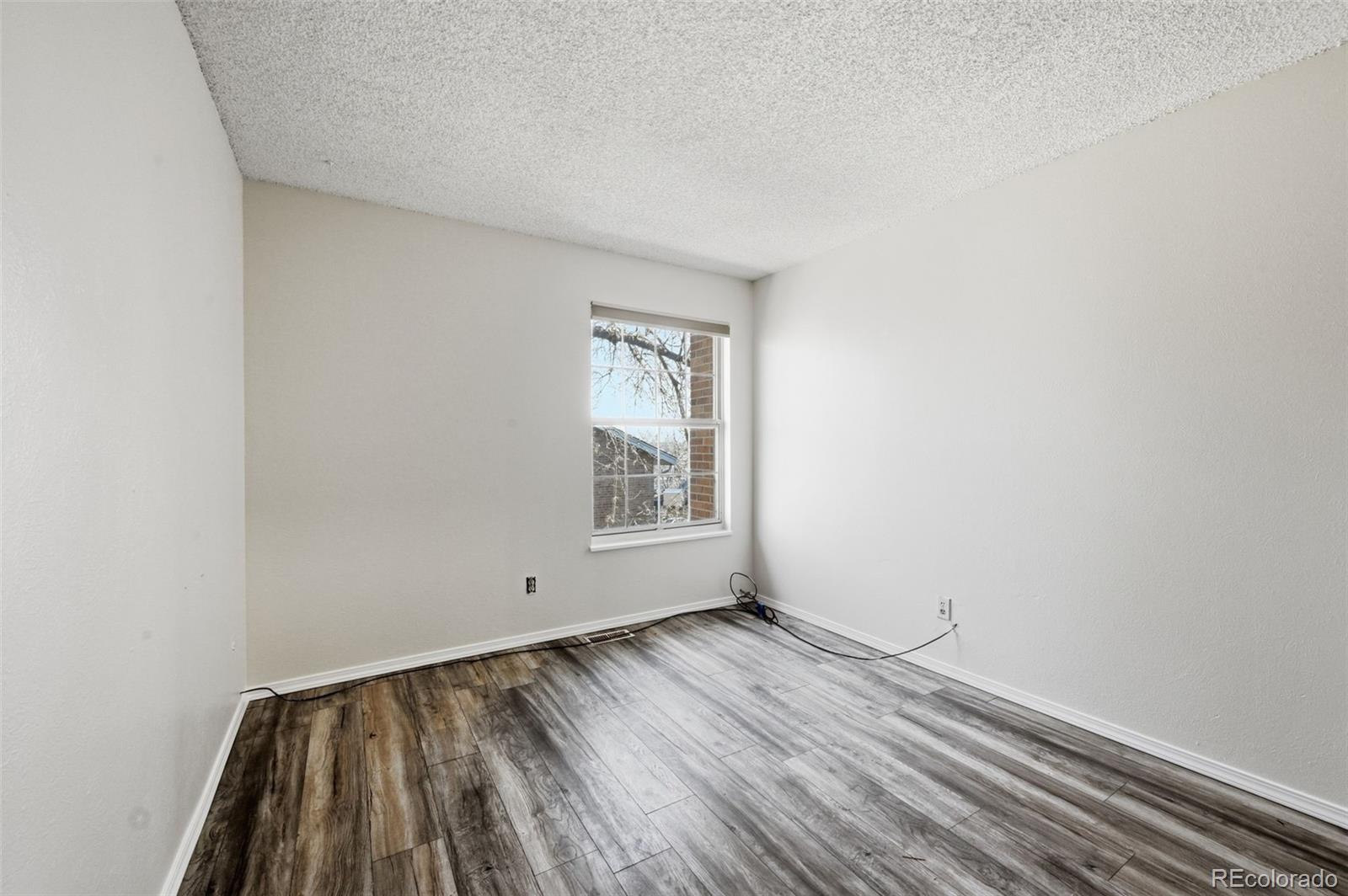 7883 Allison Way, Unit 302 Arvada, CO 80005 - Photo 19 of 29 a view of an empty room with wooden floor and a window