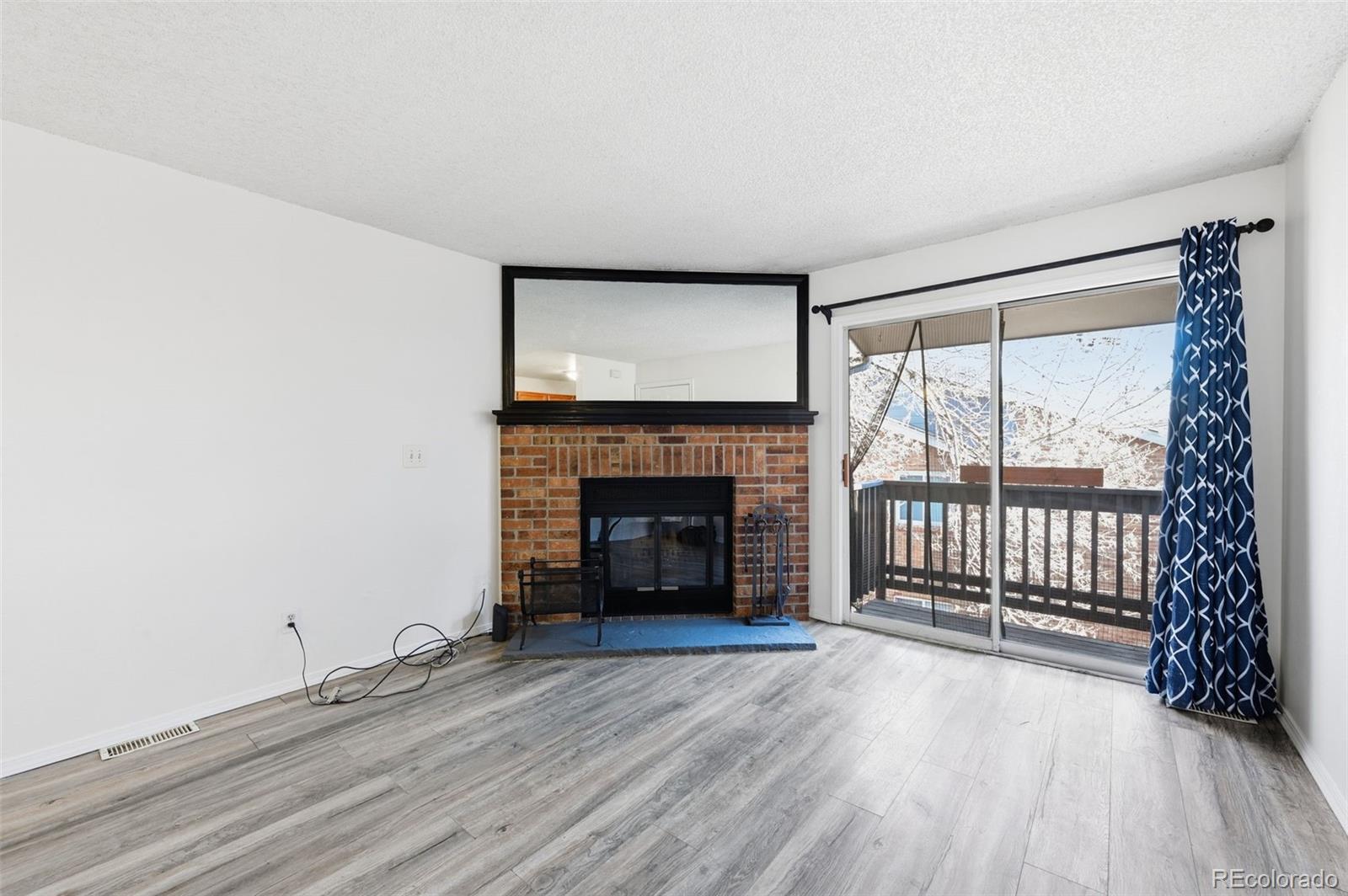 7883 Allison Way, Unit 302 Arvada, CO 80005 - Photo 6 of 29 a view of empty room with wooden floor and fireplace
