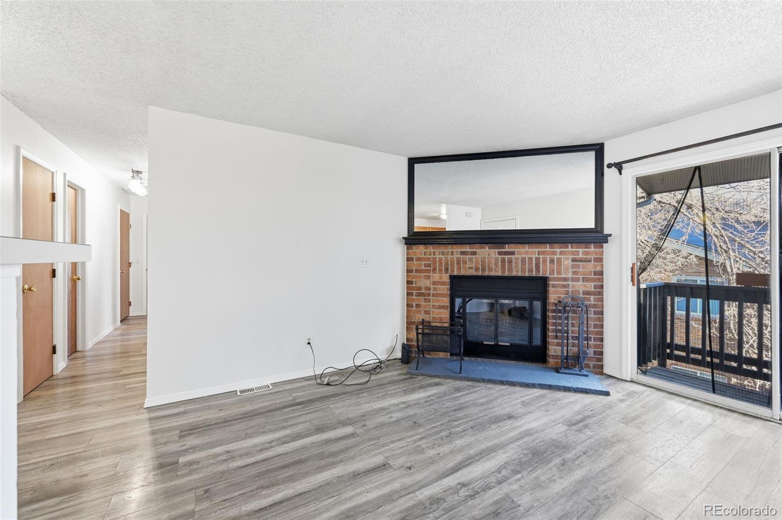 7883 Allison Way, Unit 302 Arvada, CO 80005 - Photo 7 of 29 a view of empty room with wooden floor and fireplace