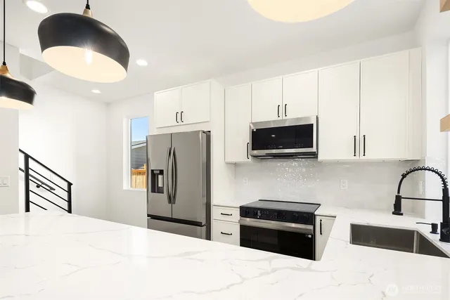 a kitchen with stainless steel appliances granite countertop a refrigerator a stove and a sink with wooden floor