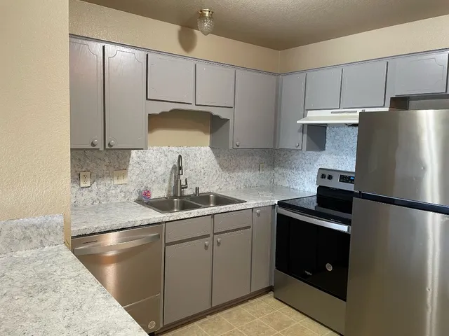 a kitchen with stainless steel appliances granite countertop a sink a refrigerator and a stove
