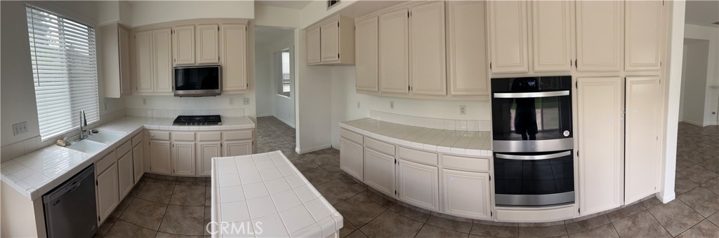 11306 Trailstone Court Riverside, CA 92505 - Photo 35 of 47 a kitchen with white cabinets and stainless steel appliances