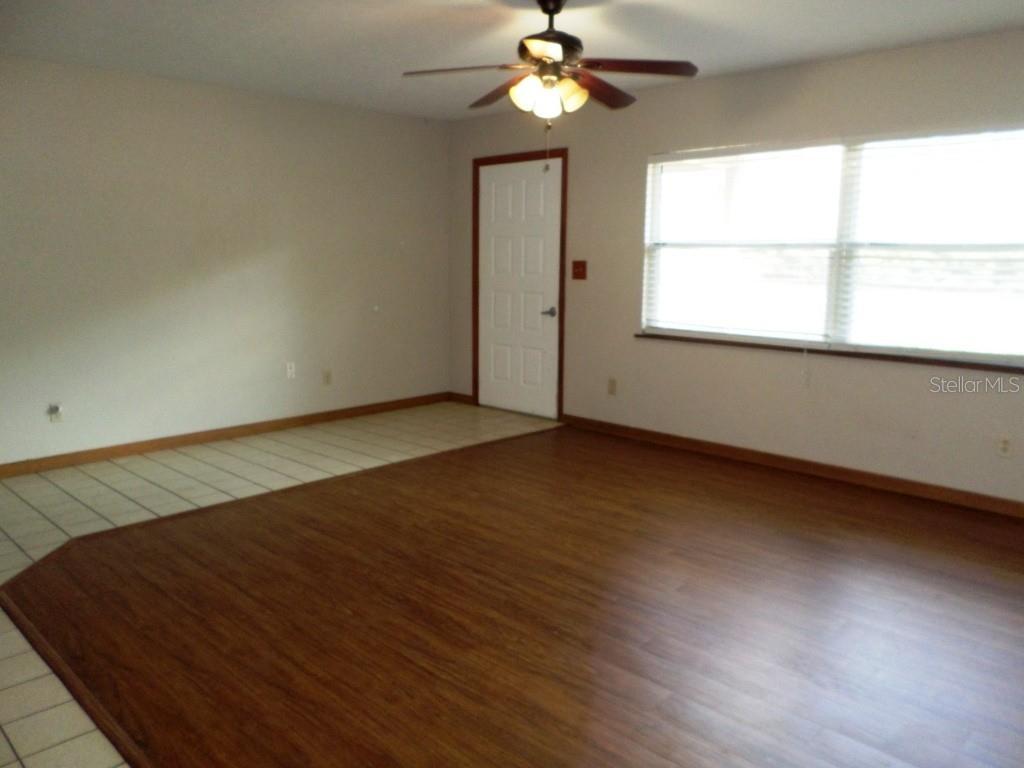 11606 Kennesaw Road Dunnellon, FL 34431 - Photo 5 of 33 an empty room with wooden floor chandelier fan and windows