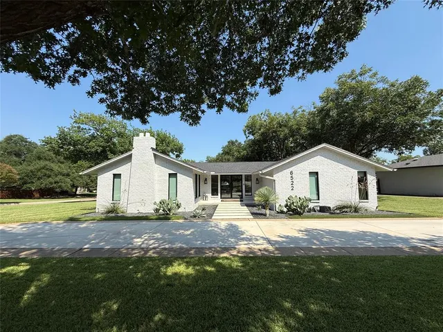 a view of a yard in front of a house with large trees