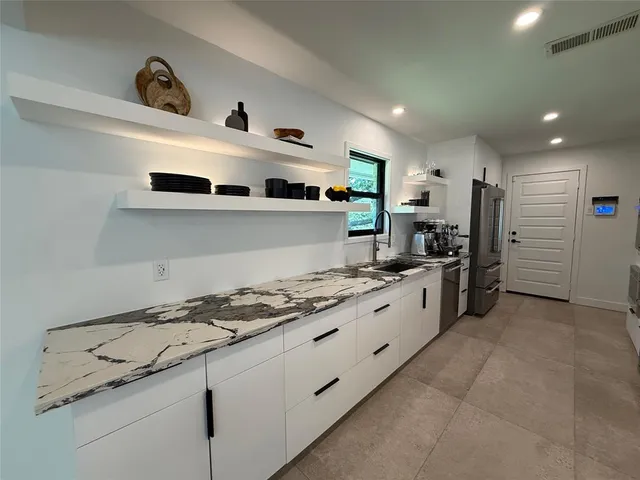 a kitchen with stainless steel appliances a refrigerator a sink and cabinets