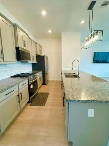 a kitchen with stainless steel appliances granite countertop a sink a stove and a refrigerator