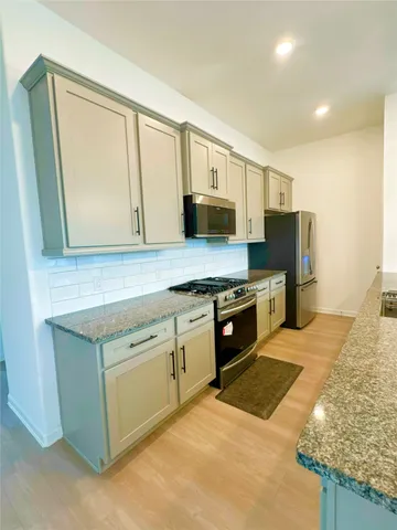 a kitchen with stainless steel appliances granite countertop a stove a sink and a microwave