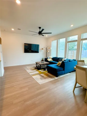 a living room with furniture a flat screen tv and a large window