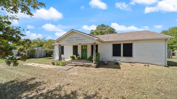 a front view of house with yard and trees in the background