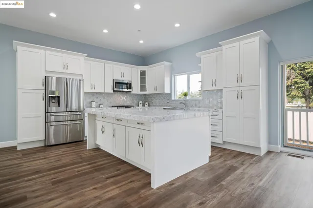 a kitchen with granite countertop white cabinets and white stainless steel appliances