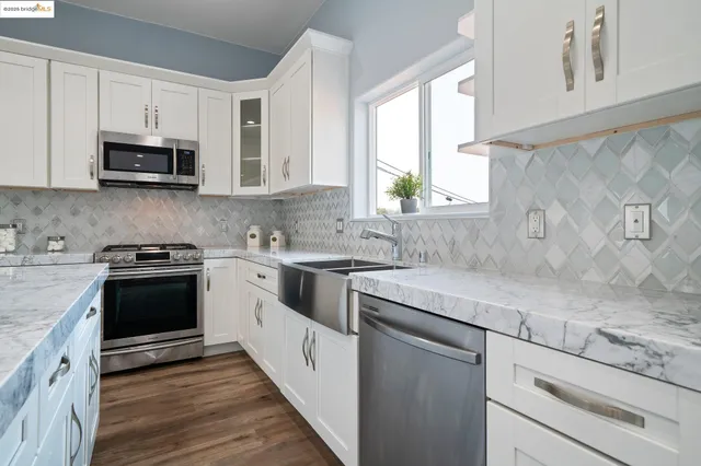 a kitchen with stainless steel appliances granite countertop white cabinets a sink and a stove