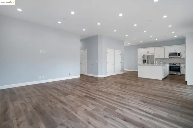 a view of kitchen with kitchen island wooden floor center island and stainless steel appliances