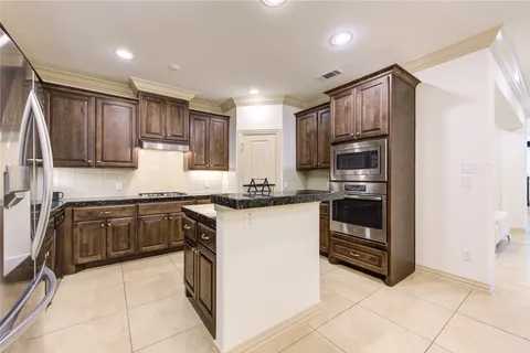 a kitchen with kitchen island granite countertop a refrigerator and a sink