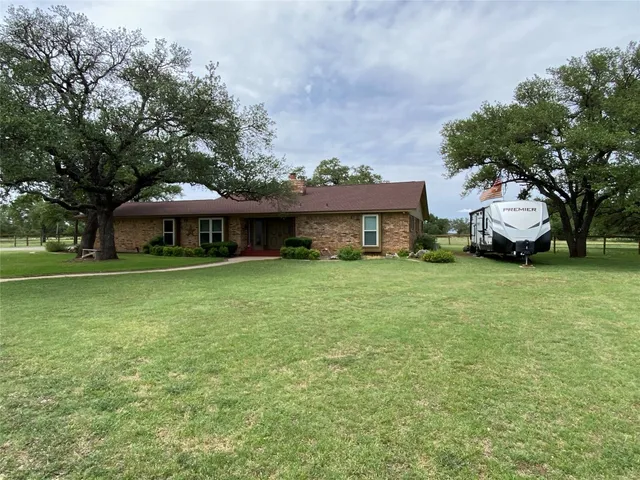 a front view of a house with a garden and trees