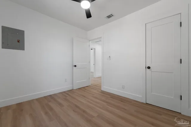 an empty room with wooden floor cabinet and windows