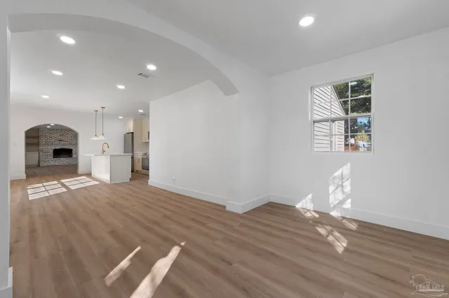 a view of empty room with wooden floor and kitchen view