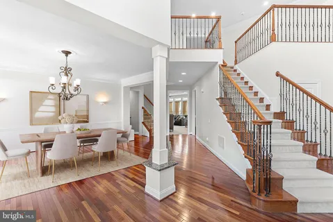 a dining room with wooden floor a chandelier a wooden table and chairs