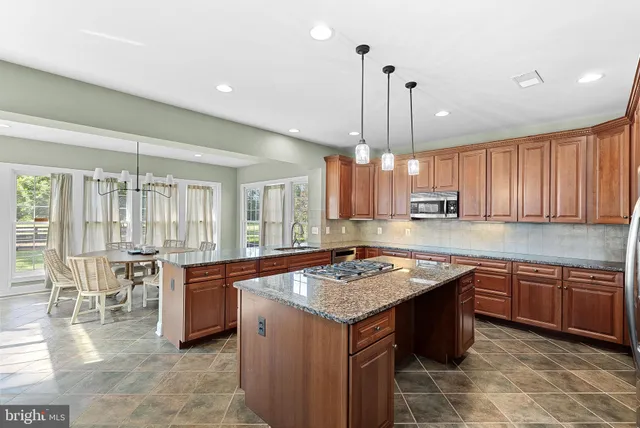 a kitchen with a stove a sink dishwasher a kitchen island with chairs and wooden cabinets