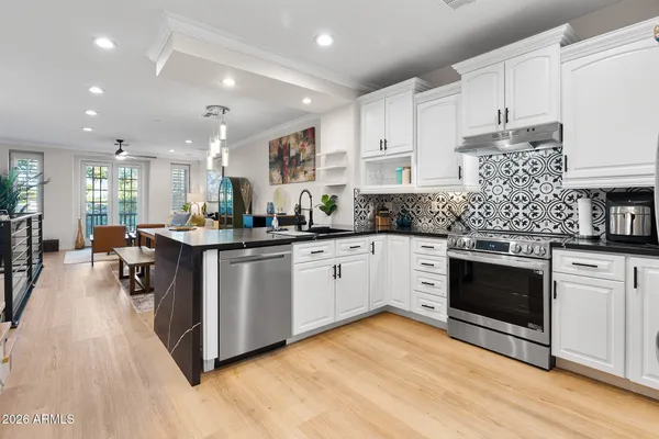 a kitchen with stainless steel appliances kitchen island granite countertop a stove top oven a sink a counter space and cabinets