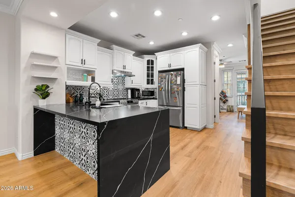 a kitchen with stainless steel appliances granite countertop a sink a stove and a wooden floors