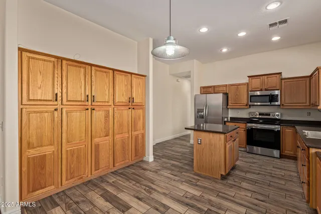 a kitchen with kitchen island granite countertop wooden cabinets and stainless steel appliances