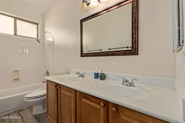 a bathroom with a toilet sink vanity granite and mirror