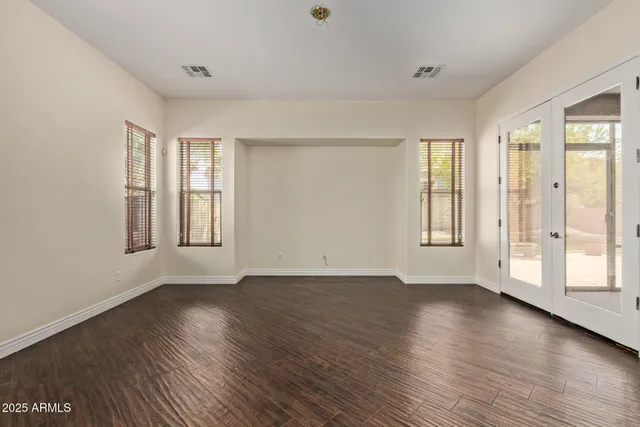 an empty room with wooden floor and windows with curtains view